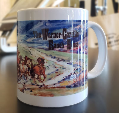 Photo of a Warner-Carrillo souvennir mug printed with a Marjorie Reed painting of the stage arriving at Warner-Carrillo.